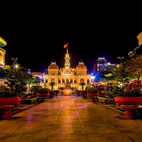 Ночью у Городской ратуши.<br/>
Здание городского совета (Ho Chi Minh City Hall) Хошимина известно под разными именами. До 1954 года оно называлась просто городским советом. В промежуток времени с 1954 года по 1975 год здание носило название Городской Совет Сайгона. С 1975 года в здании стал располагаться народный комитет Хошимина. Здание в молочно-белых и жёлтых тонах расположено в конце бульвара Нгюен Хюэ на улице Ле Тхань Тон. Строительство здания было начато в марте 1898 и завершено в 1908 году. Считается, что здание было спроектировано известным французским архитектором Гарде, он также участвовал в работе над интерьером главного зала и прямоугольных боковых крыльев. На крыше здания находится знаменитая колокольня, расположенная на пьедестале, напоминающем пирамиду. Колокольные башни заимствованы из архитектурного стиля эпохи Возрождения, подобные башни можно видеть почти на всех крышах городских советов в большинстве европейских городов. Сегодня это действующее правительственное здание, куда не допускается никто, кроме государственных служащих и уборщиков. Здание совета выстроено в колониальном стиле, напоминающем о провинциальных французских городах. Хотя туристам не разрешается проходить внутрь, они могут рассмотреть здание снаружи, считается, что оно особенно красиво смотрится ночью в свете фонарей.