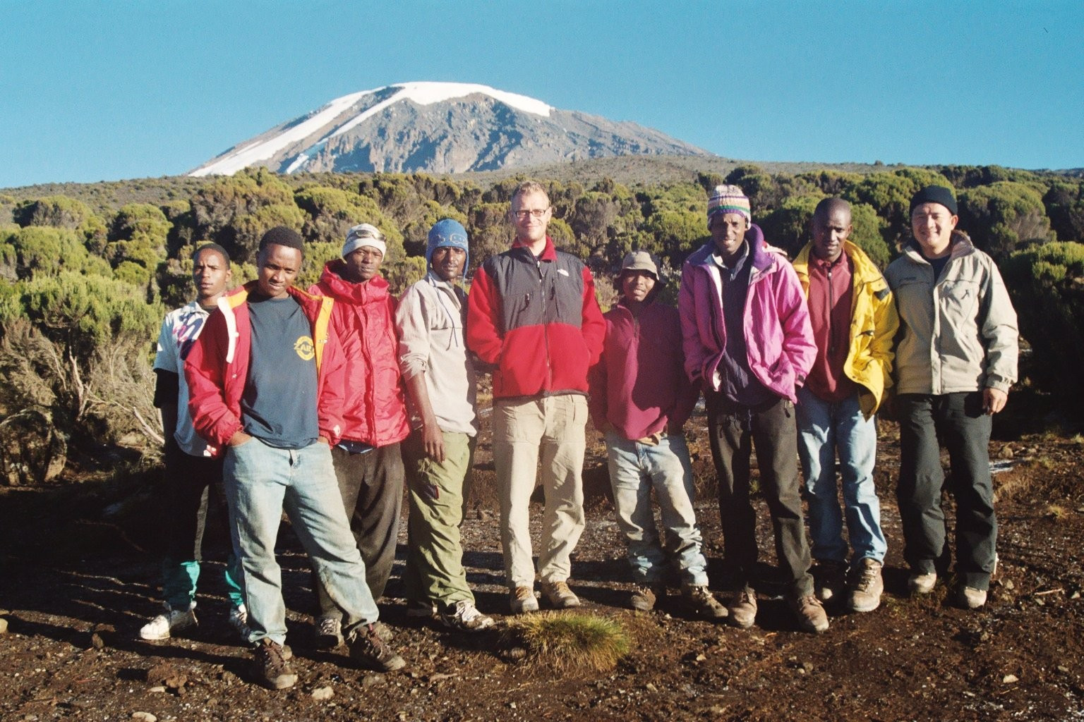 Group shot of Dirk, myself, and our Tanzanian guides and porters at 12000-foot Millenium Camp with views of the 19340-foot glacier-clad Kibo summit, on Mount Kilimanjaro, Tanzania