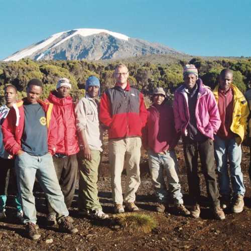 Group shot of Dirk, myself, and our Tanzanian guides and porters at 12000-foot Millenium Camp with views of the 19340-foot glacier-clad Kibo summit, on Mount Kilimanjaro, Tanzania