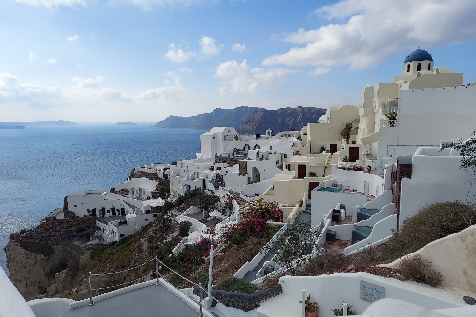 Dramatic white church and cliff-side dwellings on the island of Santorini — one of the Cyclades Islands in the Aegean Sea, Greece.