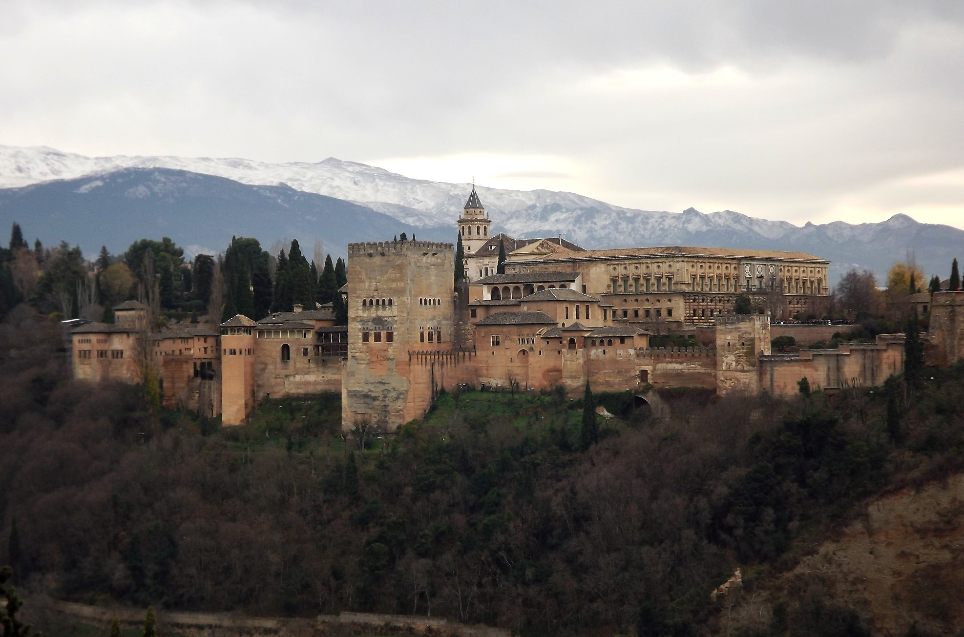 Majestic Alhambra Palace and fortress built by the Islamic Moors who ruled Spain for 7 centuries, seen with the backdrop of snow-capped Sierra Nevada mountains, in Granada, Spain.
