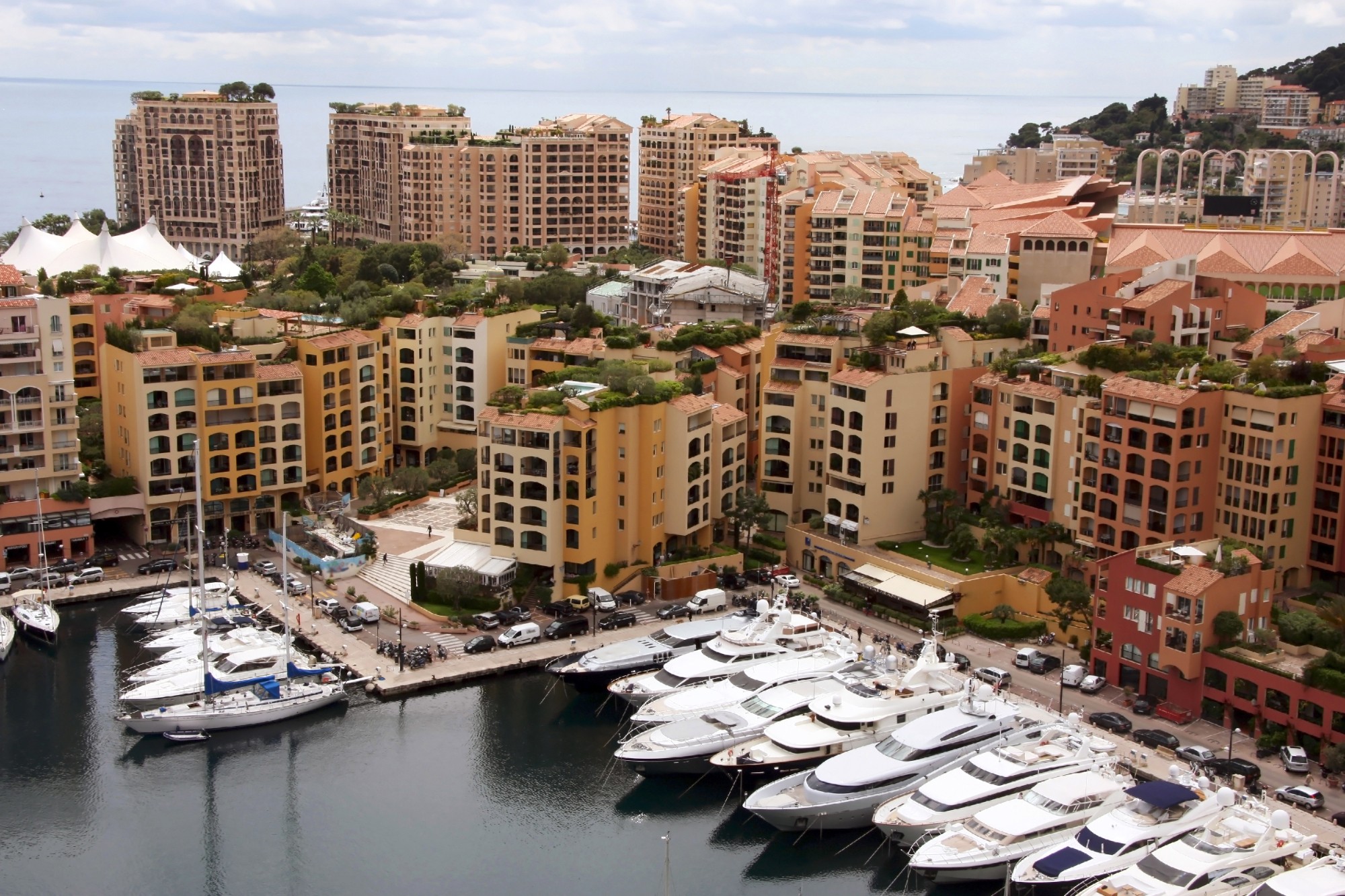 Mooring with yachts near many-storeyed buildings behind which the sea is visible