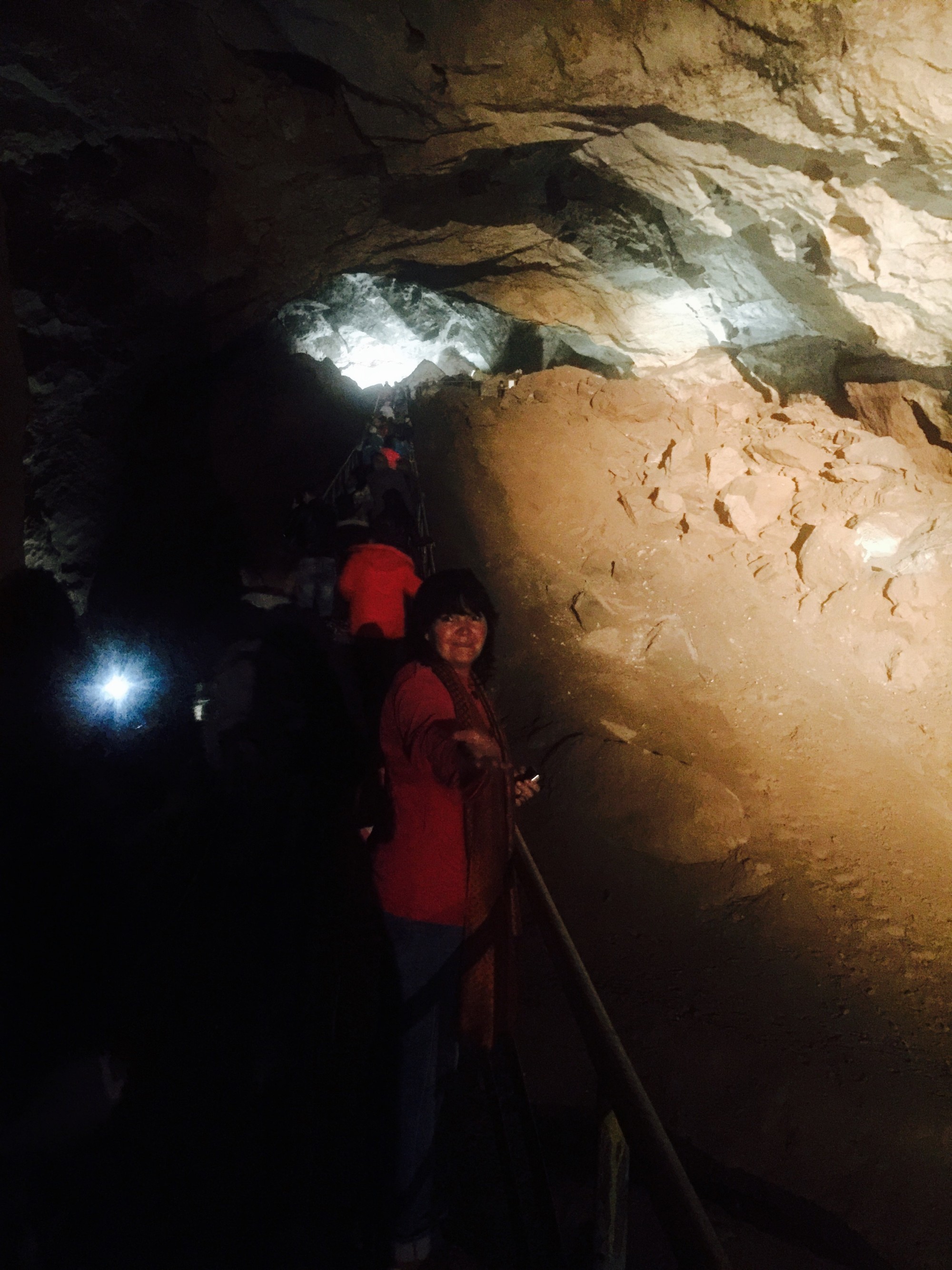 Группа туристов следует по мосту в самом большом зале пещеры 