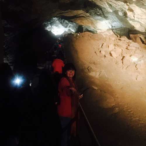 Группа туристов следует по мосту в самом большом зале пещеры 