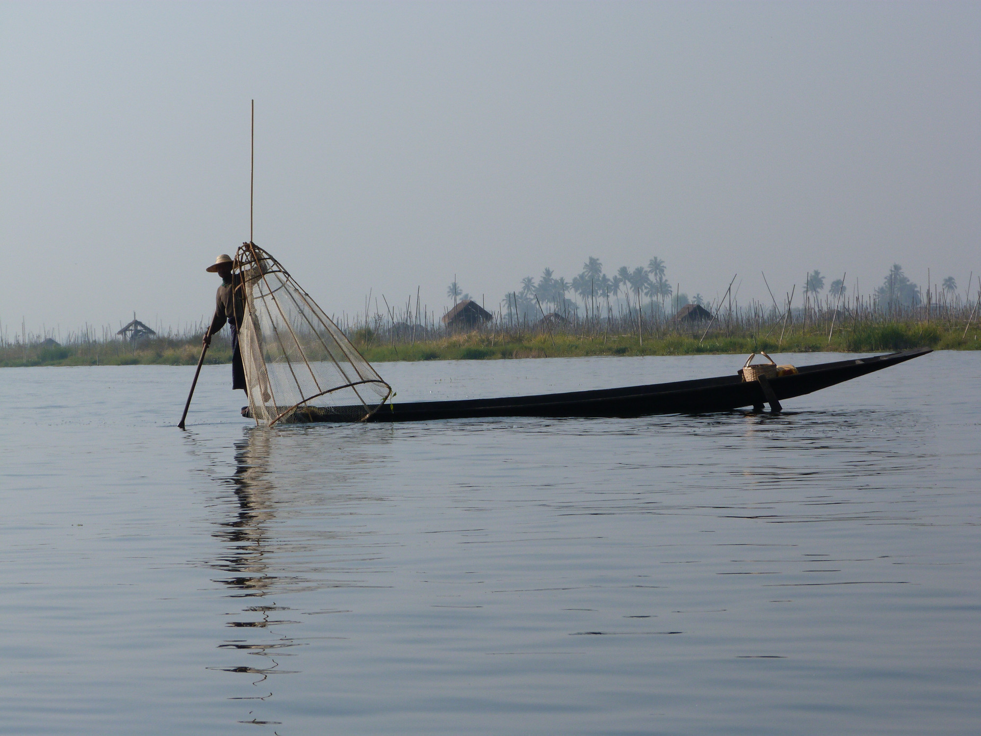 Fisherman using single leg oar/pole to move boat
