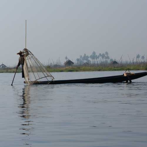 Fisherman using single leg oar/pole to move boat