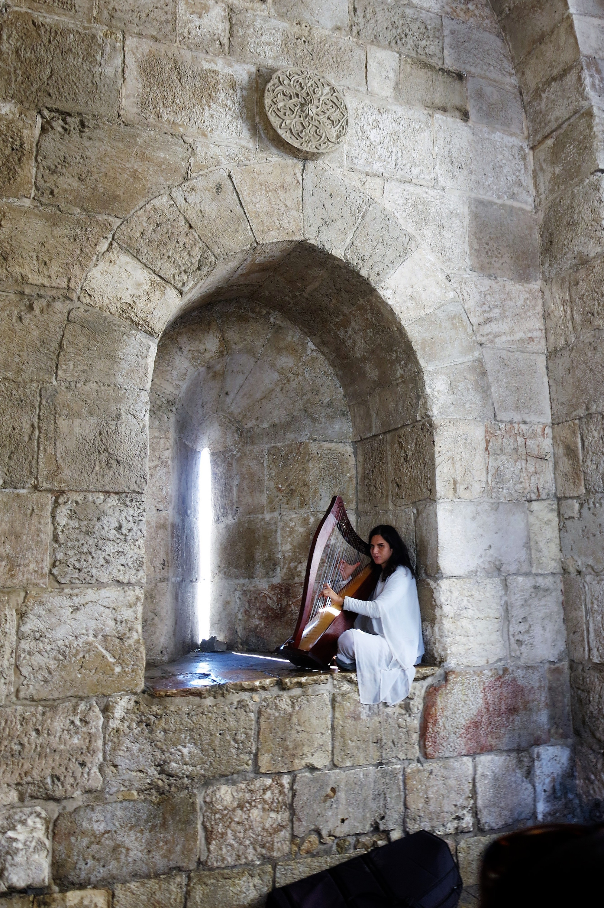 A girl plays the harp seated in a window of the Jaffa Gate